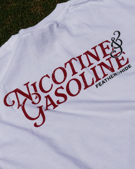 White t-shirt with red and black text 'Nicotine & Gasoline' on a grassy background