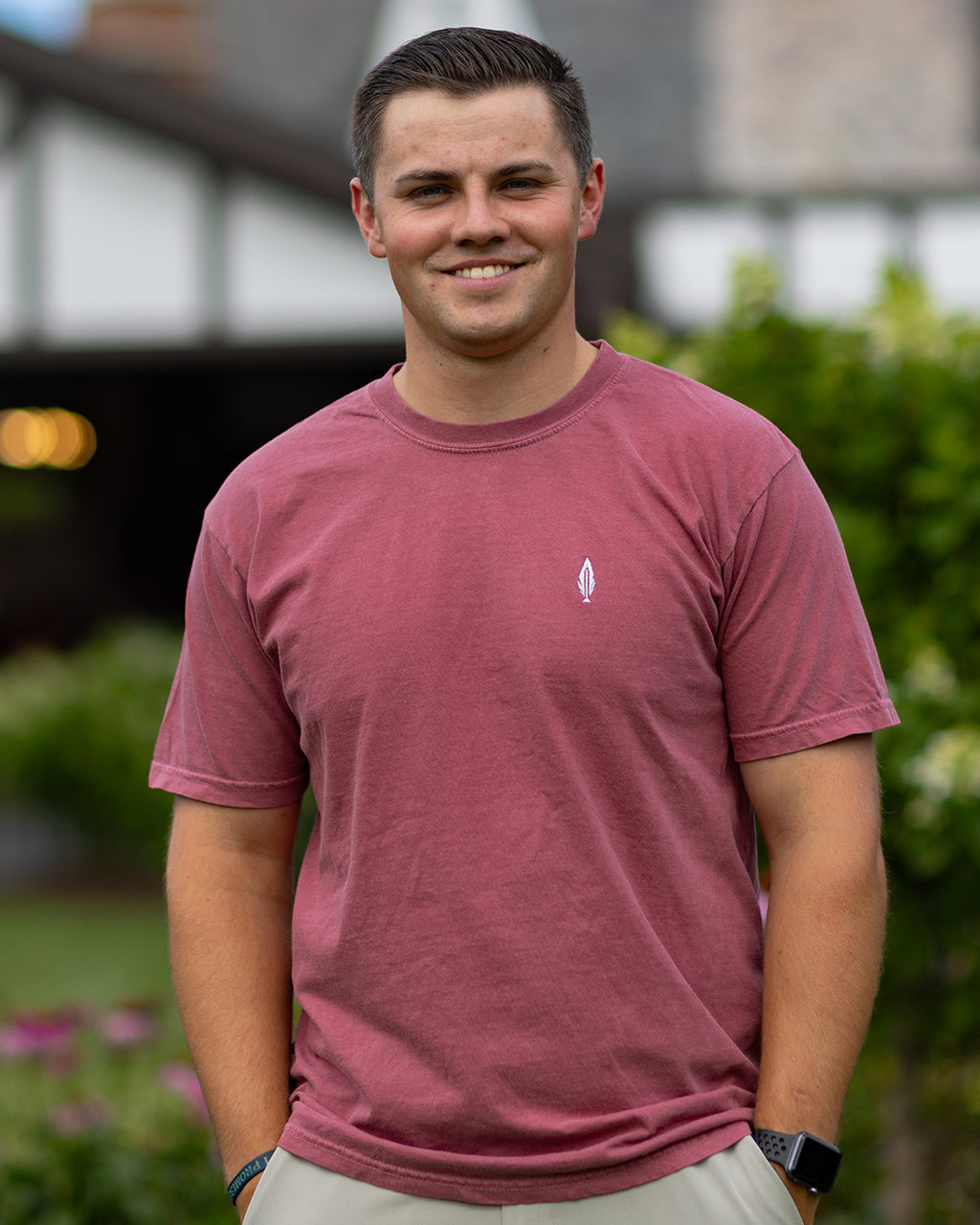 man wearing a red feather and hide golf shirt