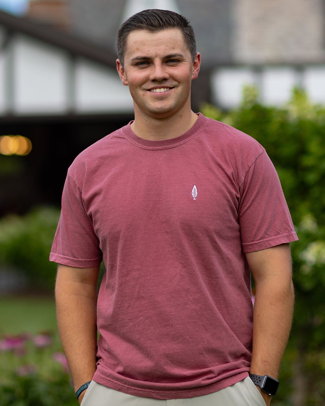 man wearing a red feather and hide golf shirt