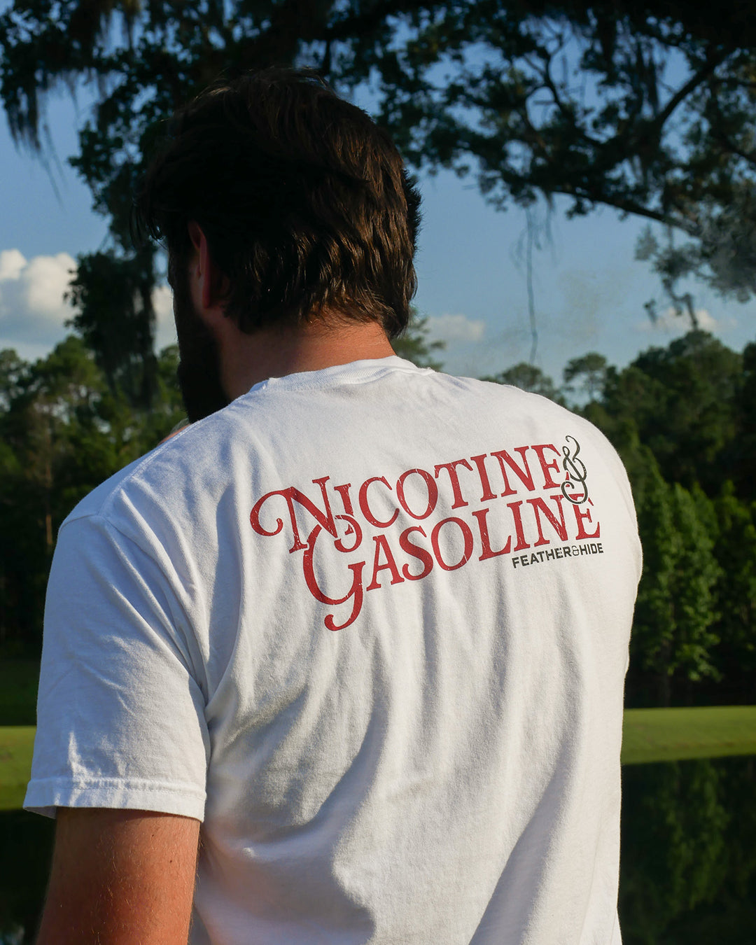 Person wearing a white t-shirt with 'Nicotine & Gasoline' text on the back, standing outdoors.