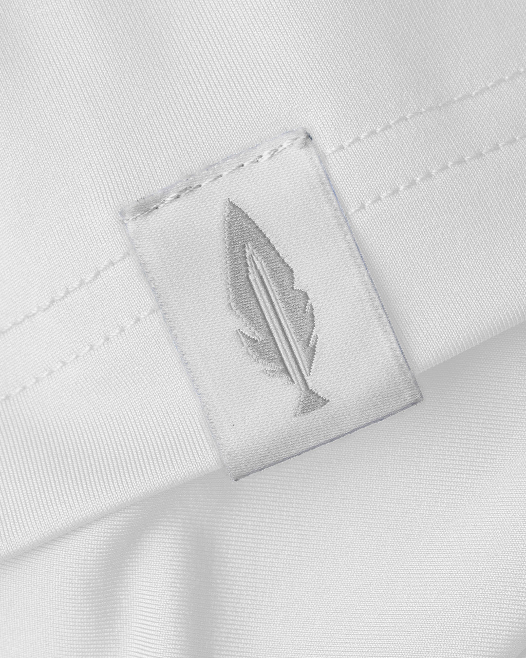 Close-up of a white shirt with the Feather and Hide logo