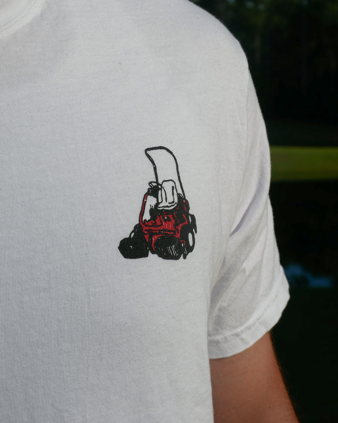 White t-shirt with a black and red graphic on the sleeve against a dark background