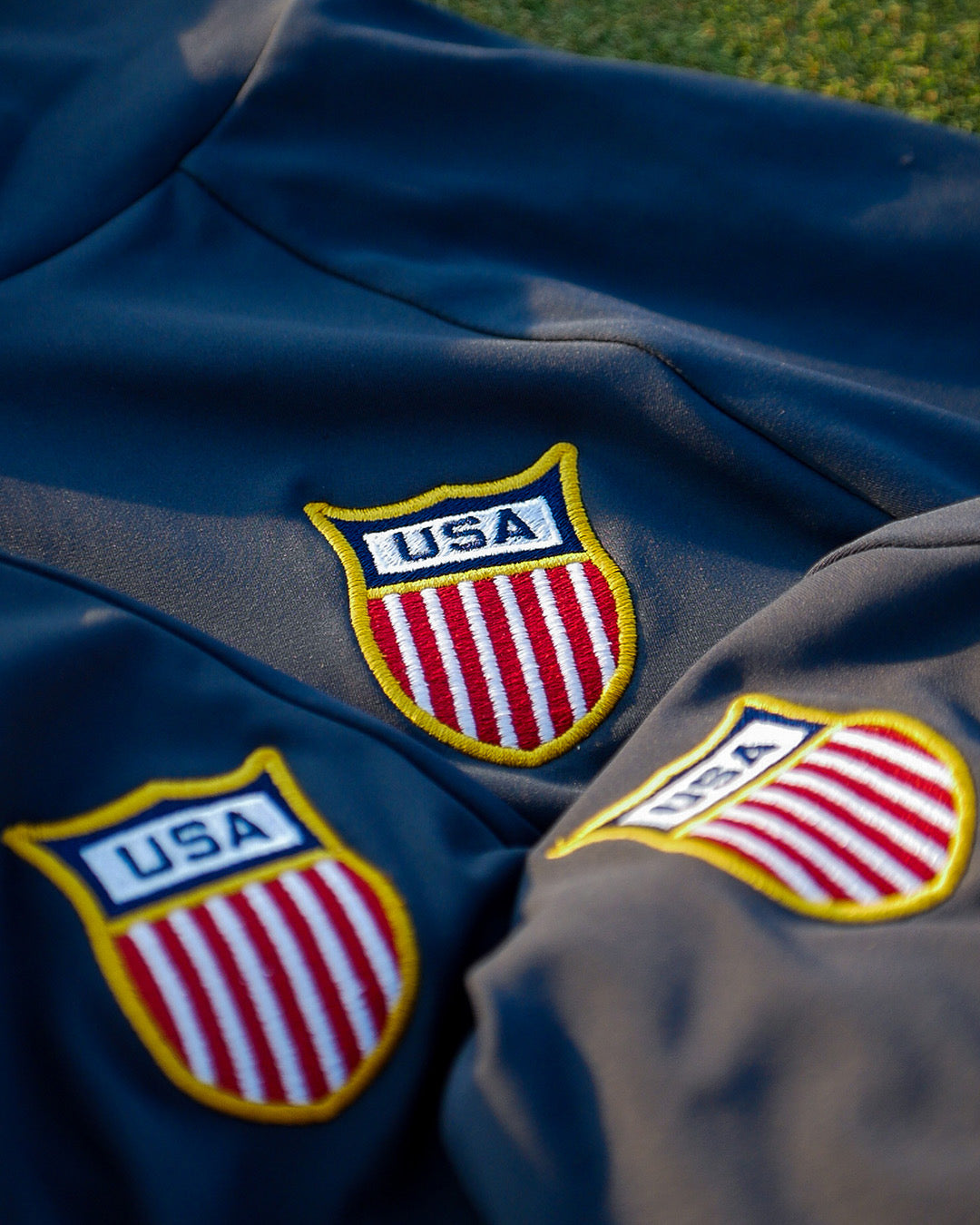 Close-up of a feather and hide golf hoodie with USA logos on a grass background